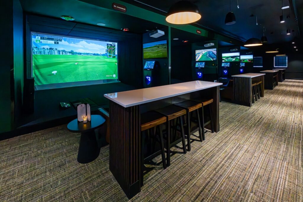 a golf simulator bay with a spectator bar top at the ParT Barn