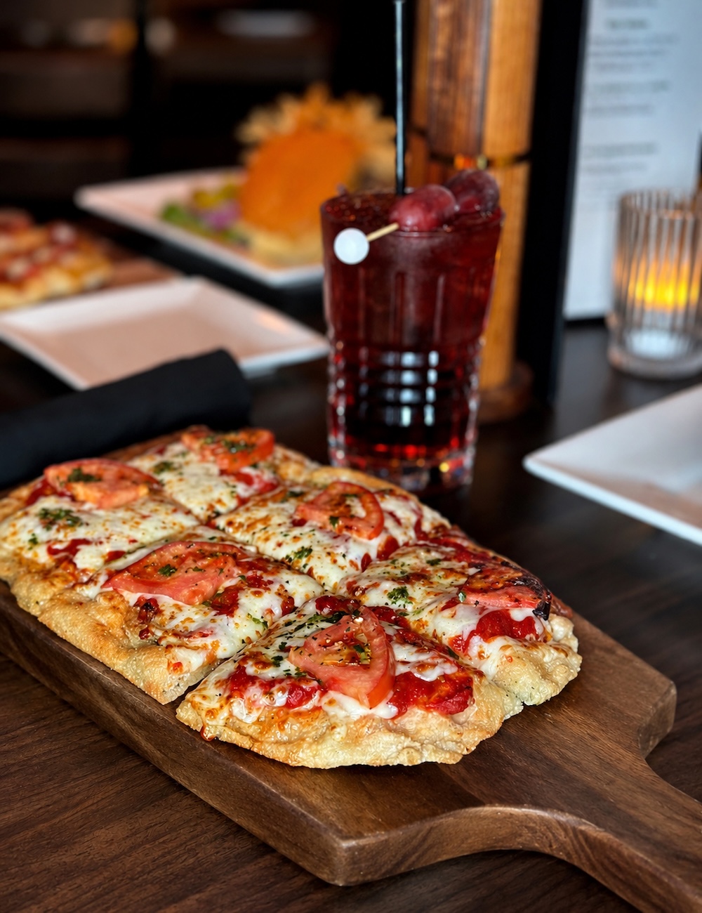 flatbread pizza on a wooden cutting board with a drink at the ParT Barn